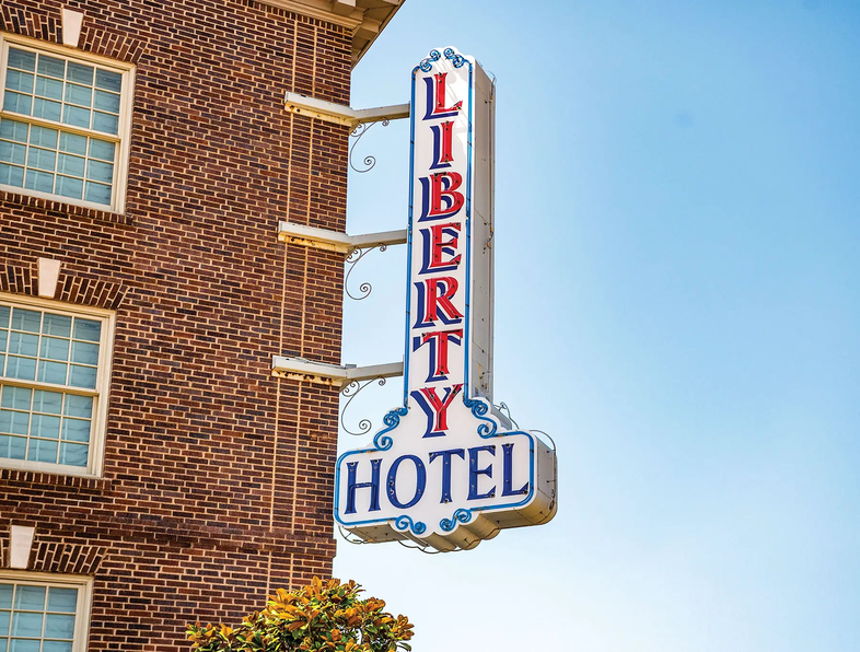Cleburne Liberty Hotel sign hanging off the corner of a brick building
