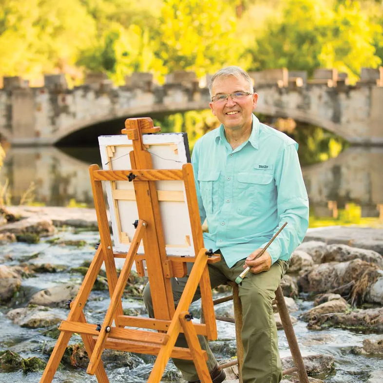 Clemente Guzman with his easel set up in a rocky creek