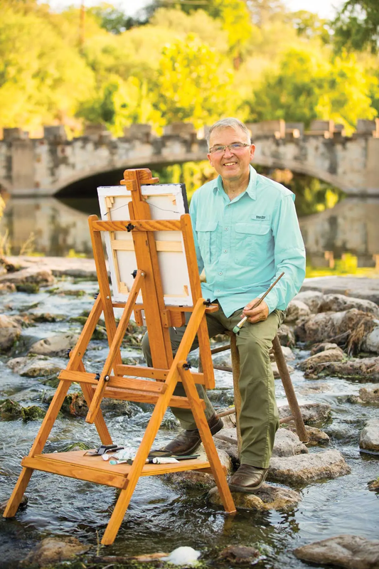 Clemente Guzman with his easel set up in a rocky creek