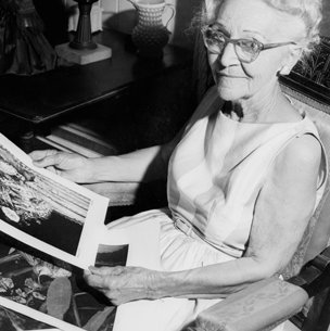 Connie Hagar black and white photo of her sitting in chair looking a pictures of birds