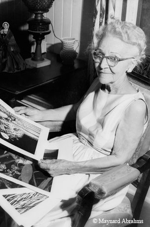 Connie Hagar black and white photo of her sitting in chair looking a pictures of birds