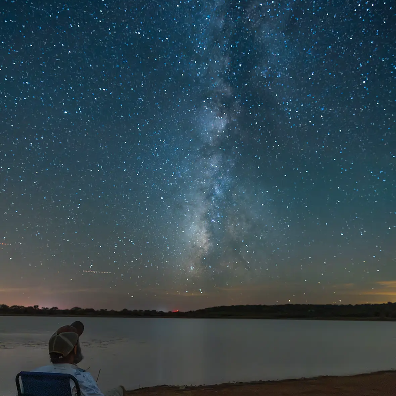 Man sitting in chair with dog at Cooper Breaks viewing the Milkway