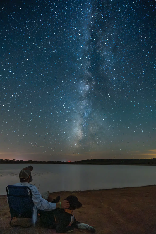 Man sitting in chair with dog at Cooper Breaks viewing the Milkway