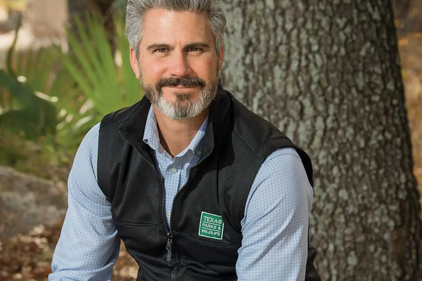 David-Yoskowitz executive Directory for TPWD sitting on a boulder in front of a tree