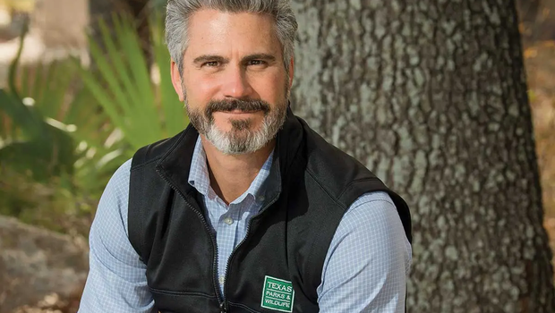 David-Yoskowitz executive Directory for TPWD sitting on a boulder in front of a tree