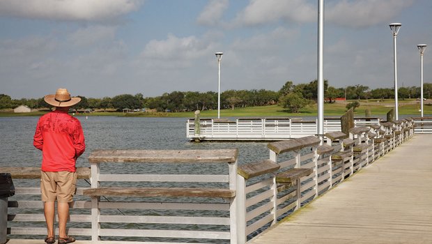 Man in red shirt and hat fishing at Lake Corpus Christi