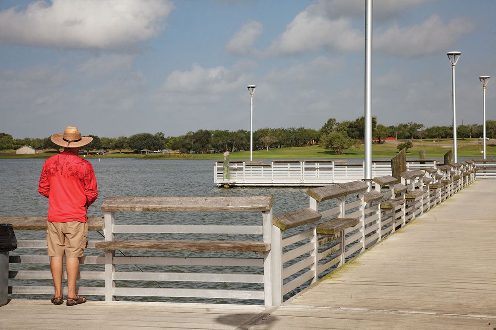 Man in red shirt and hat fishing at Lake Corpus Christi