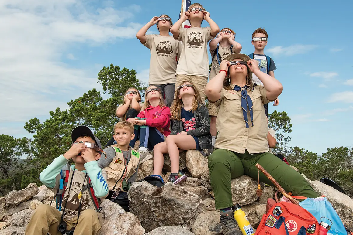 Guide and children wear solar glasses to view the solar eclipse