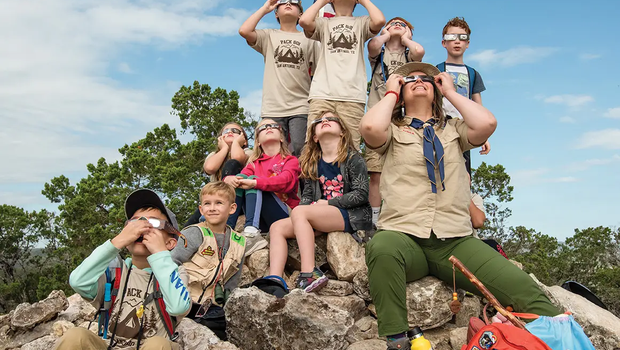 Guide and children wear solar glasses to view the solar eclipse