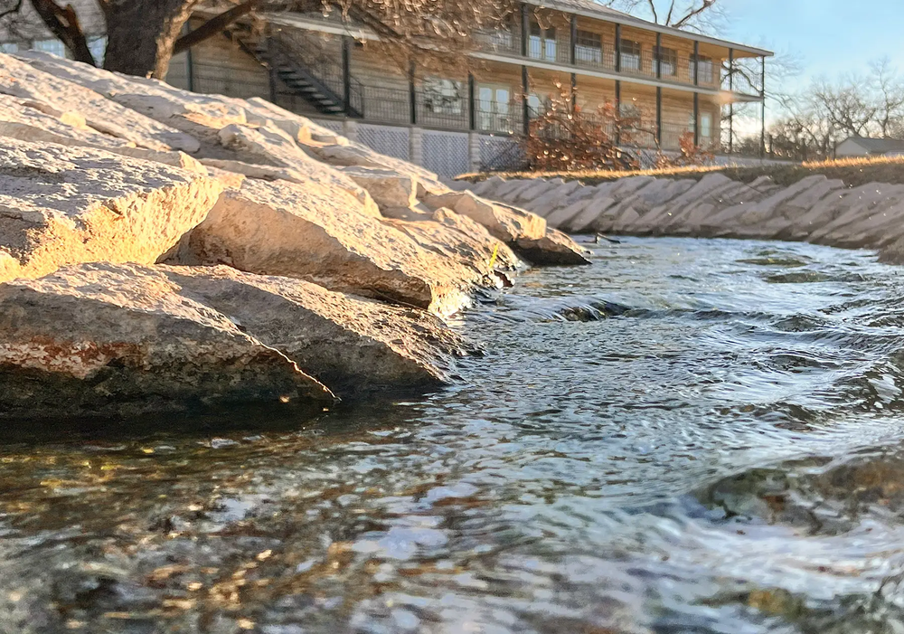 Hancock Pool with a large rock  in Lampasas Texas with the limestone hostess house in the background