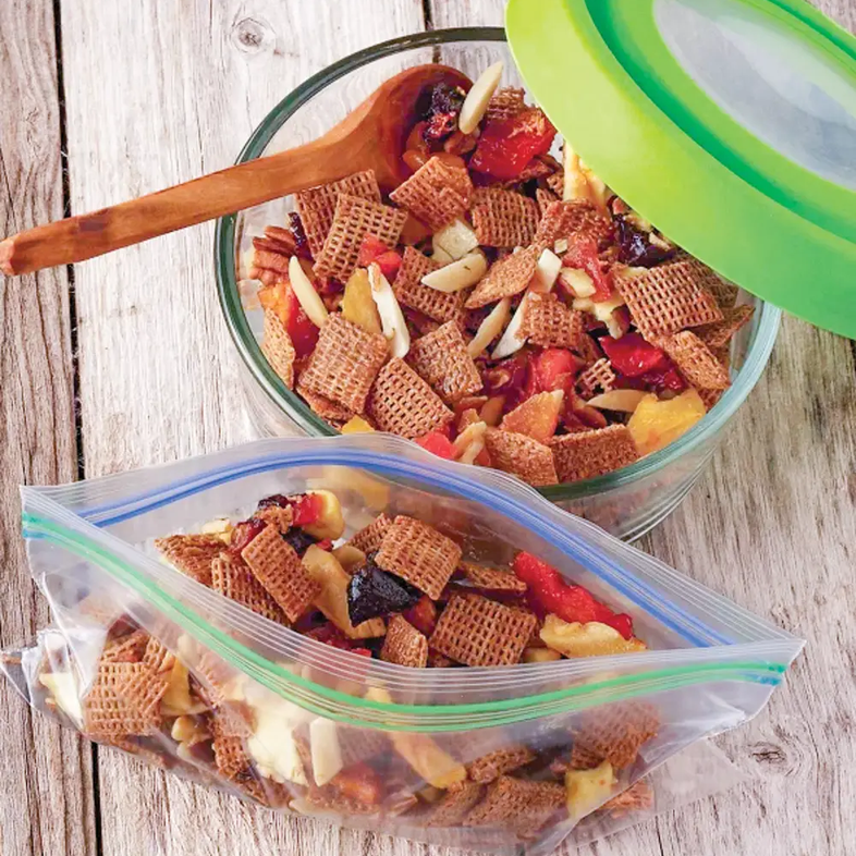 Happy Hiking Trail Mix in a glass bowl and a sandwich bag on a picnic table.