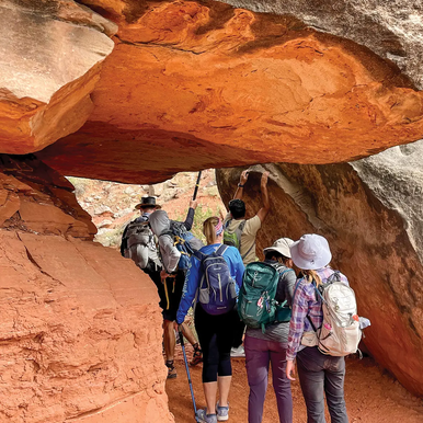 hikers walking under large boulder in Palo Duro Canyon
