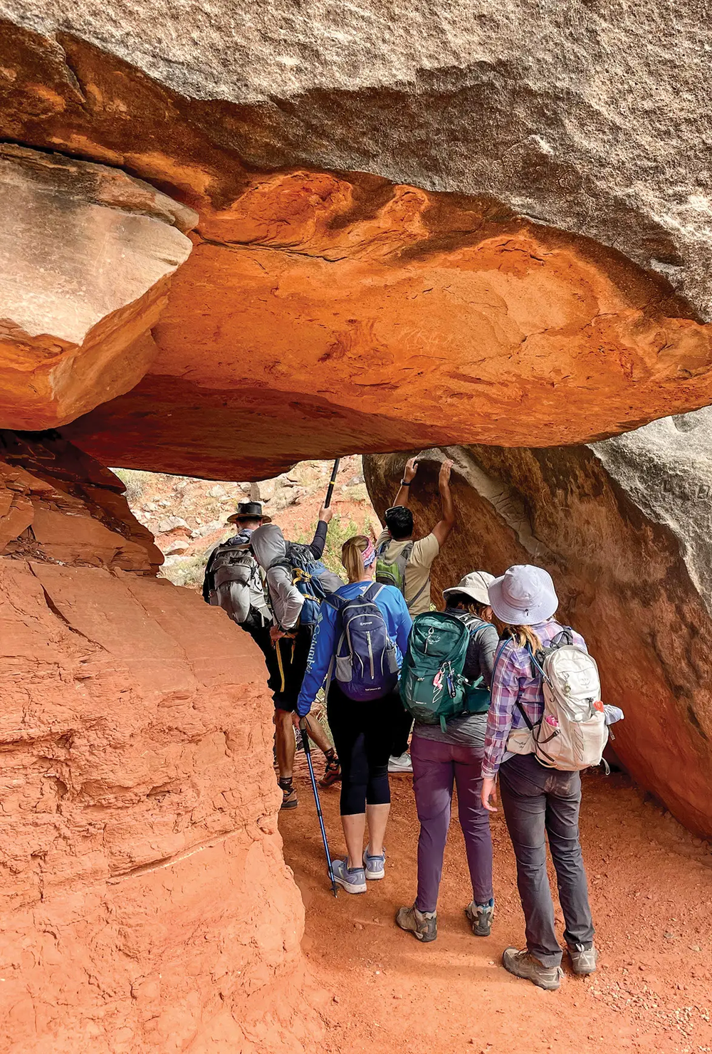hikers walking under large boulder in Palo Duro Canyon