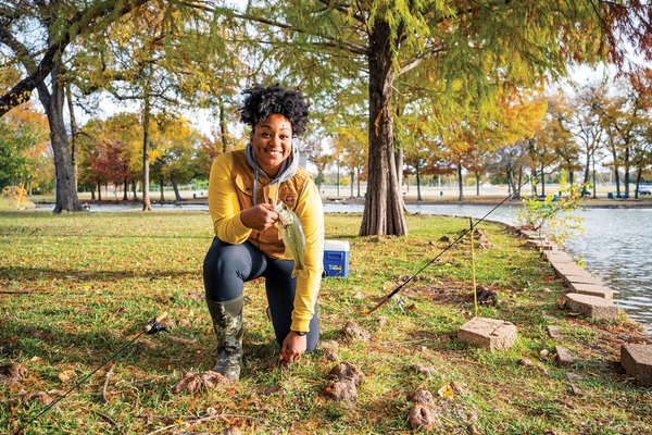 Jaz Johnson kneeling with a fish and rods