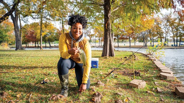 Jaz Johnson kneeling with a fish and rods