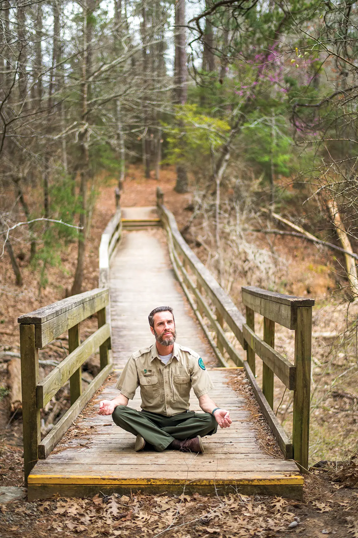 Joel Janseen a park interpreter sitting on a bridge trail meditating at Lake Livingston State Park