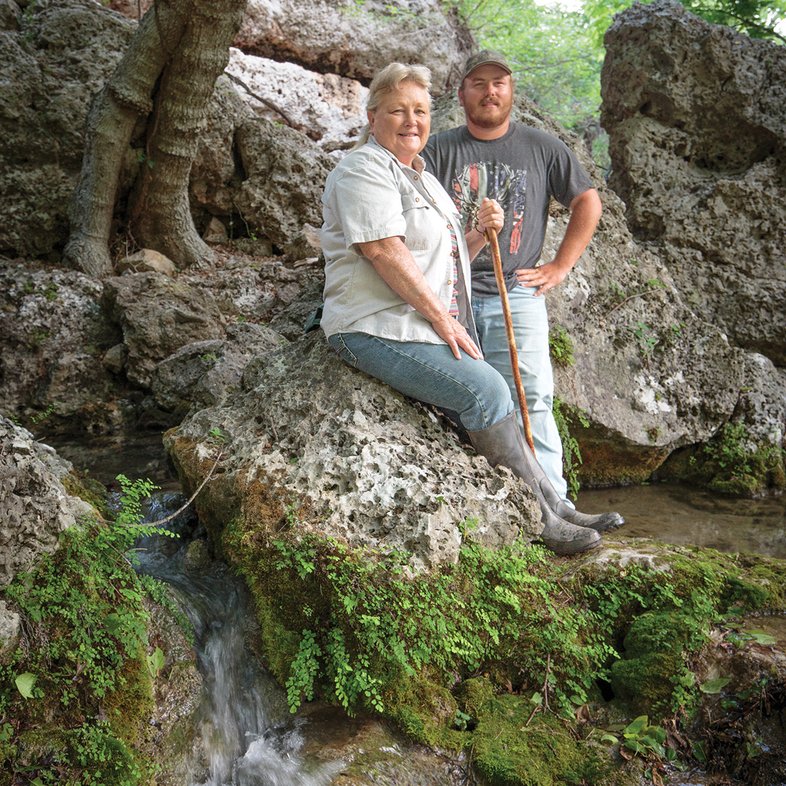 Joyce Moore and Ryan Bass leaning on a rocky hill at Honey Creek Spring Ranch