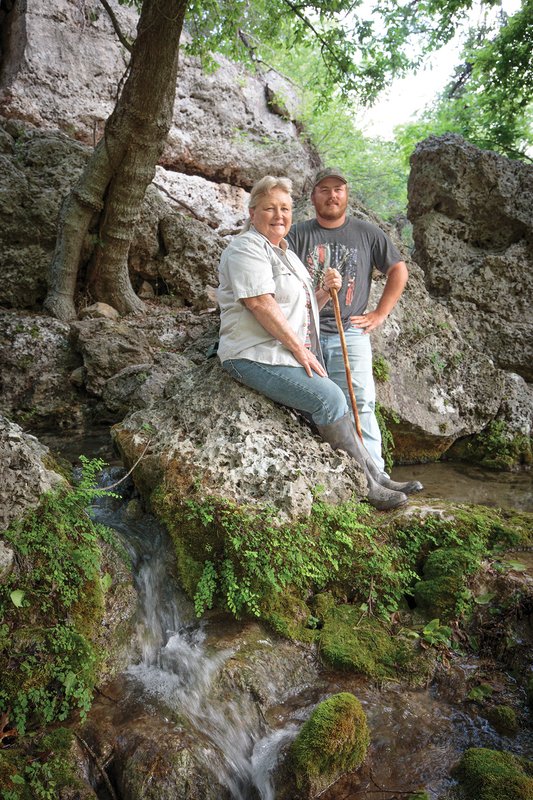 Joyce Moore and Ryan Bass leaning on a rocky hill at Honey Creek Spring Ranch