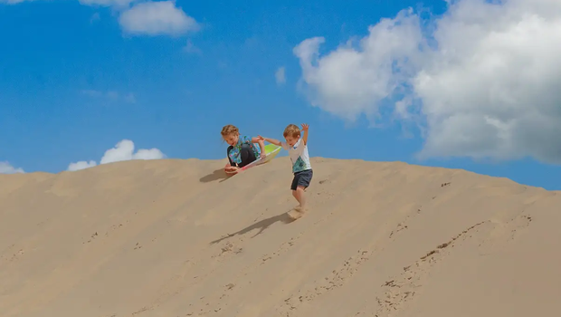 Kids sliding down the sand dunes at Monahans State Park