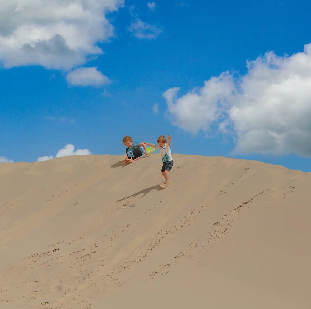 Kids sliding down the sand dunes at Monahans State Park
