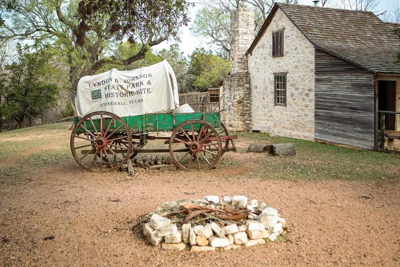 Farmhouse, covered wagon and a fire pit at Lydon B. Johnson State Park and Historical Site