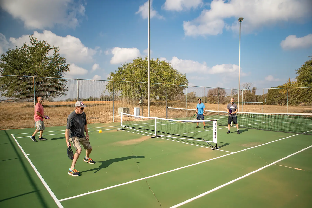 People playing doubles on a pickle ball court and the Lyndon B Johnson state park and historical site