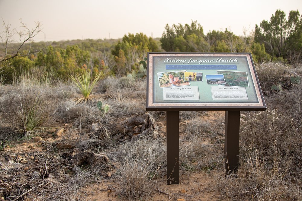 Lake Colorado City Interpretive Sign with a background of trees and catci