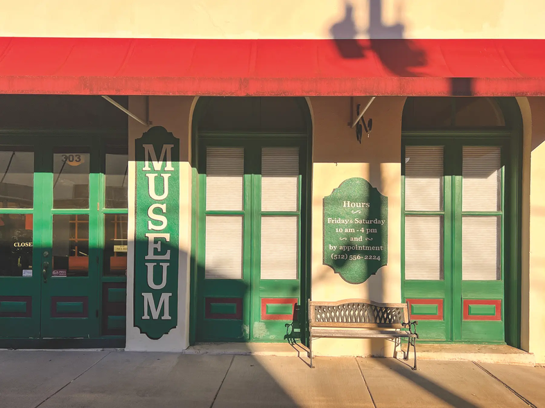 Lampasas County Museum with green doors and sign with a red awning