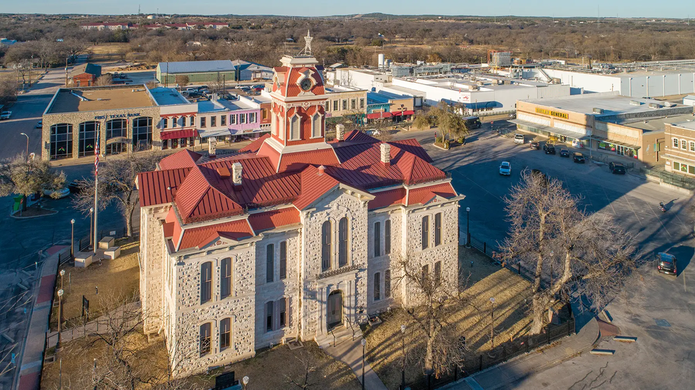 Lampasas Court House with red roof surrounded by other buildings in downtown Lampasas