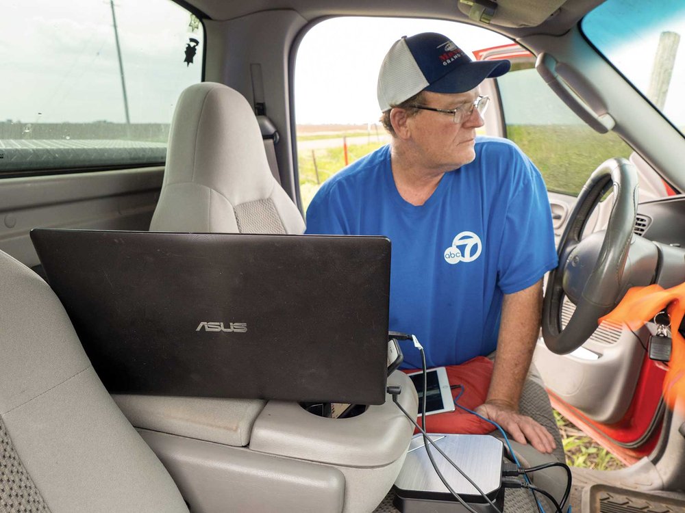 Man leaning into truck looking at a laptop.