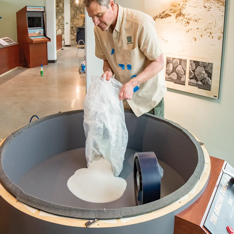 Man pouring sand into a Monahans Exhibits that showcases how dunes are made