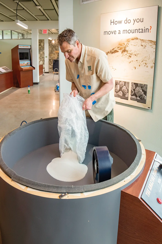 Man pouring sand into a Monahans Exhibits that showcases how dunes are made