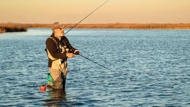 Man standing in the water fishing.