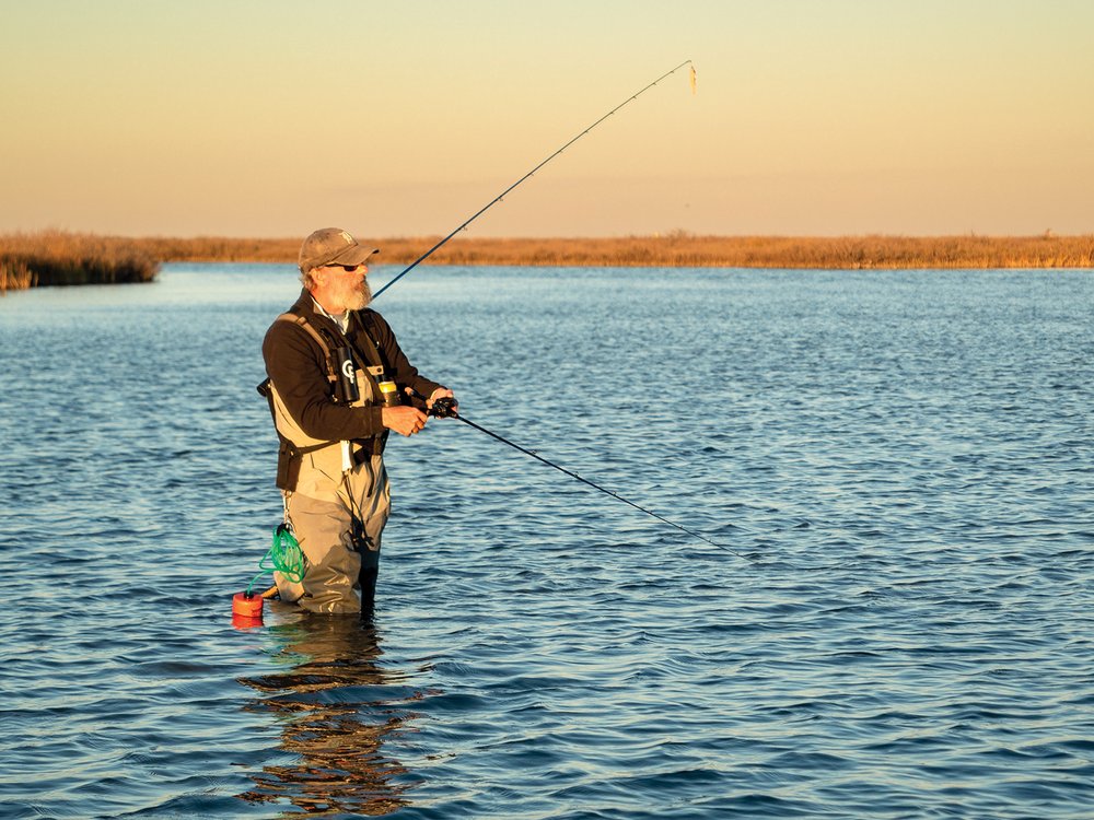 Man standing in the water fishing.