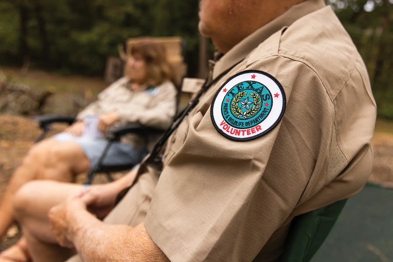 Man with a TPWD Volunteer Shirt sitting in a camping chair next to a woman