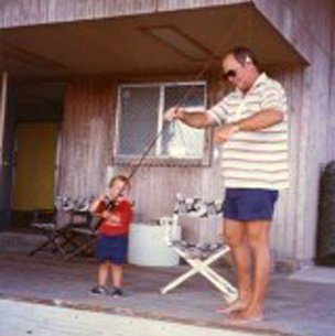 Man and child setting up fishing pole on the front porch of a house
