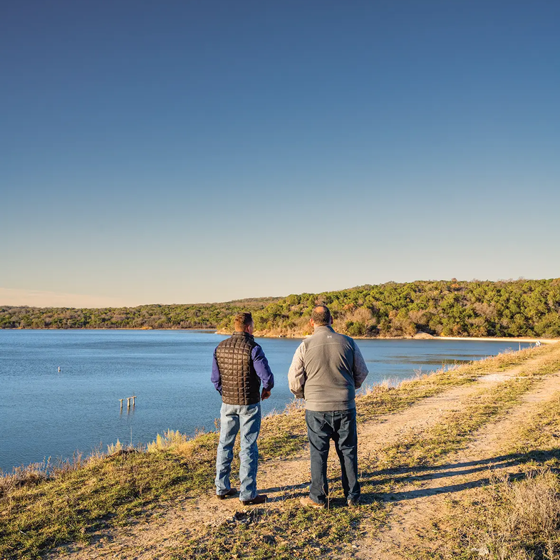 Two people walking along a trail at the Palo Pinto Overlook of the lake