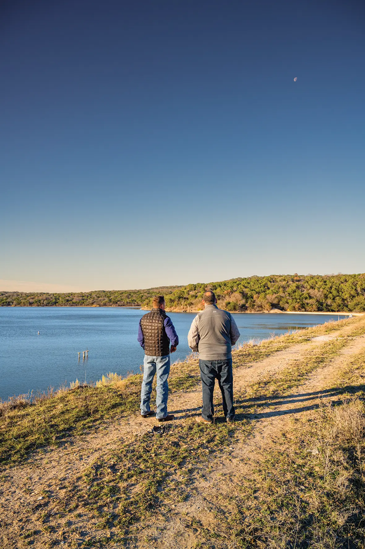 Two people walking along a trail at the Palo Pinto Overlook of the lake