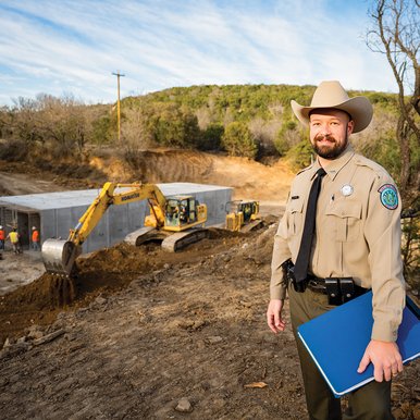 Palo pinto construction with a park employee in the forefront and a bulldozer in the background