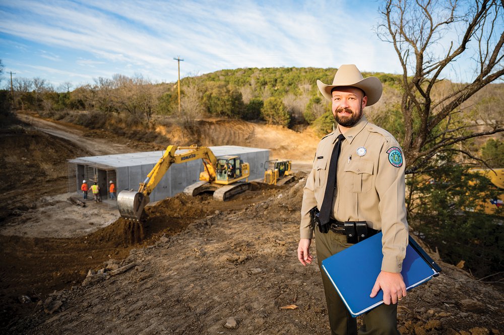 Palo pinto construction with a park employee in the forefront and a bulldozer in the background