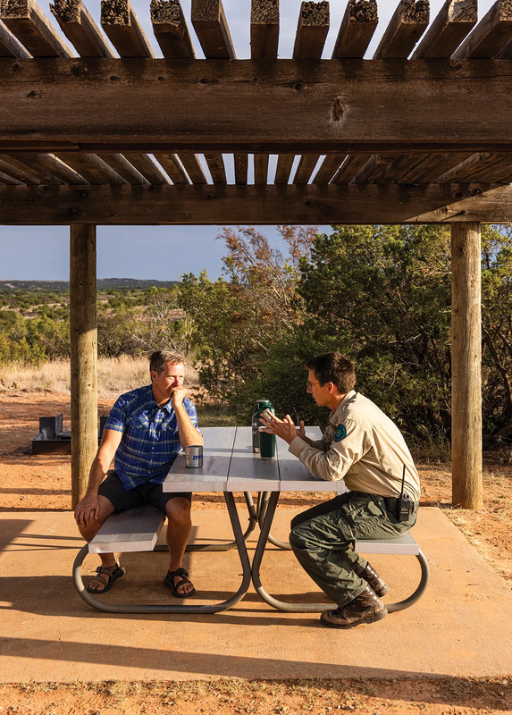 Park Ranger speaking with a man at a picnic table under a pavilion