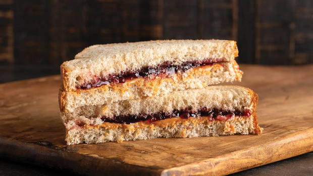 Peanut Butter and Jelly Sandwich with halves stacked on each other on a wood board