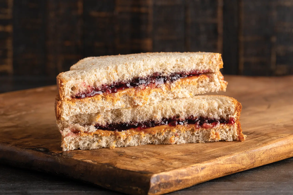 Peanut Butter and Jelly Sandwich with halves stacked on each other on a wood board