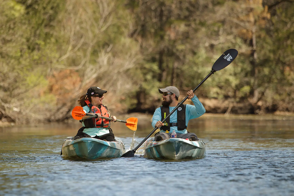 Two people Kayaking on Lake Bastrop with woods at the lake shore