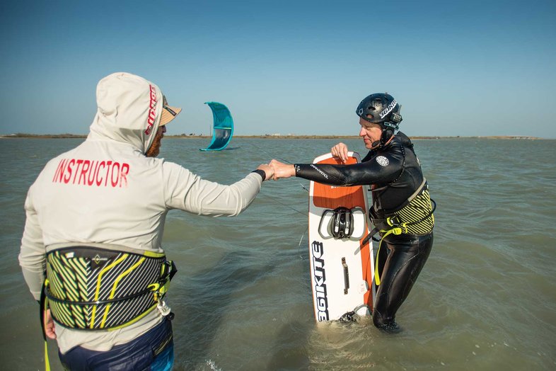 People fist-bumping in the water after kiteboarding.