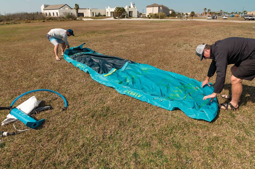 People unpacking a kite for kiteboarding.