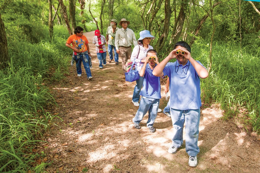 People using binoculars while birding on a trail.