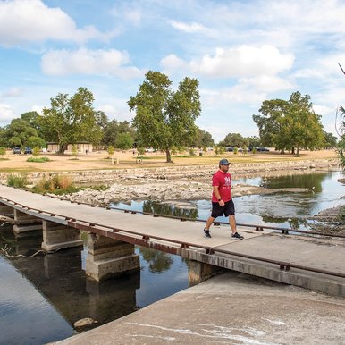 Person crossing a bridge on a trail over water.