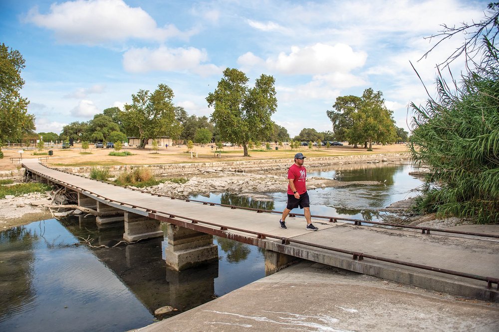 Person crossing a bridge on a trail over water.