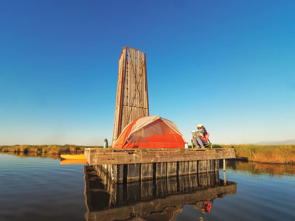 Person with a tent pitched on a floating platform at Sea Rim State Park